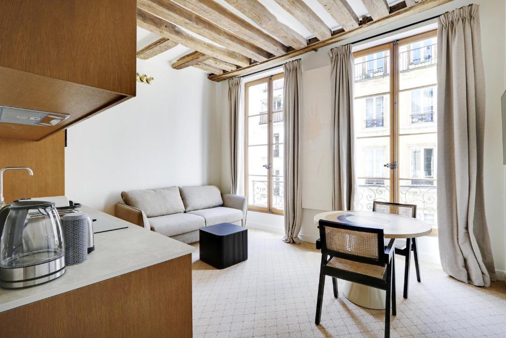 een keuken en een woonkamer met een bank en een tafel bij Pick A Flat's Apartments in Louvre - Rue Saint Honoré in Parijs