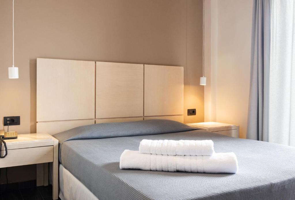 a bedroom with a bed with two white towels on it at Plaza Hotel in Loutraki