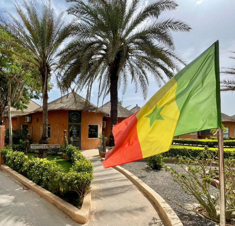 a flag in front of a house with palm trees at Agence Adjana Resort in Saly Portudal