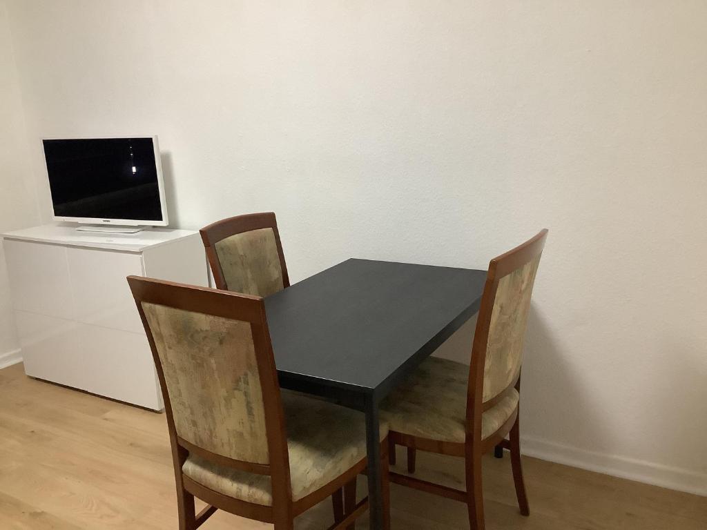 una mesa negra con 4 sillas y un ordenador en un escritorio en City-Wohnung 12a, en Brühl
