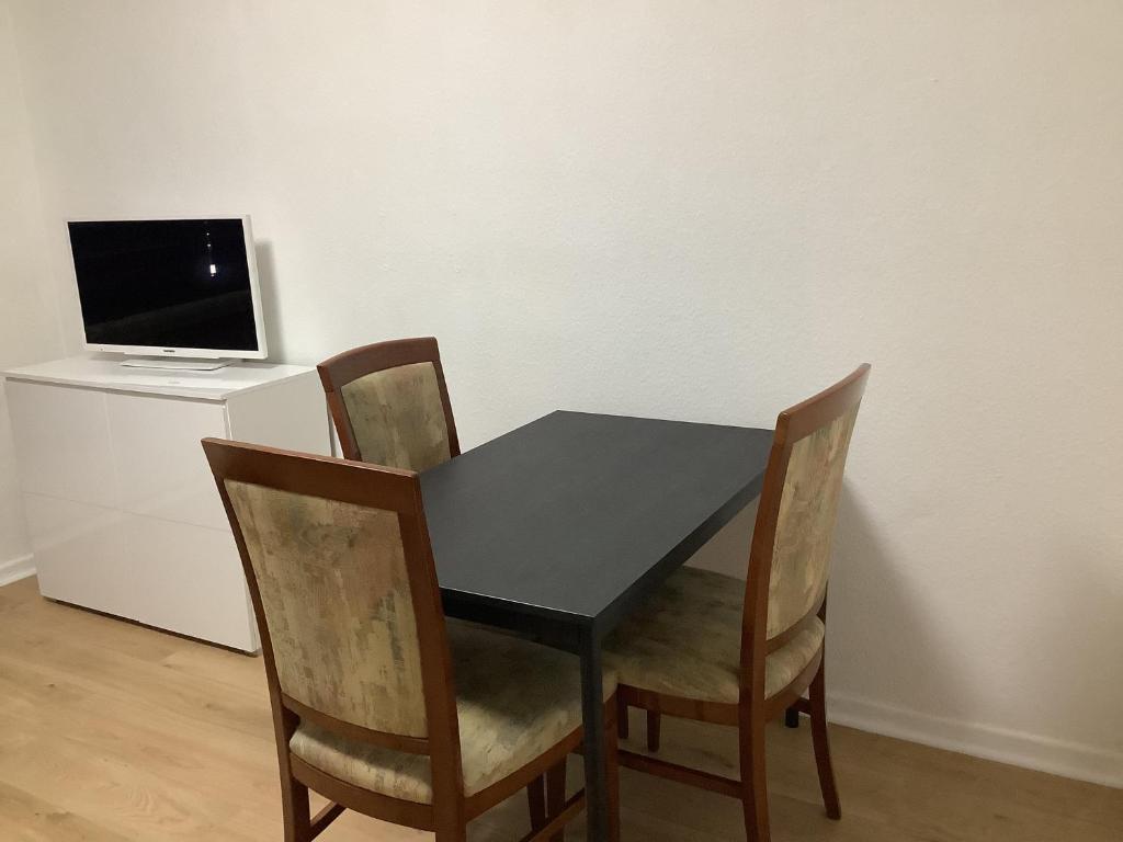 Una mesa negra con cuatro sillas y una computadora en un escritorio. en City-Wohnung 12a, en Brühl