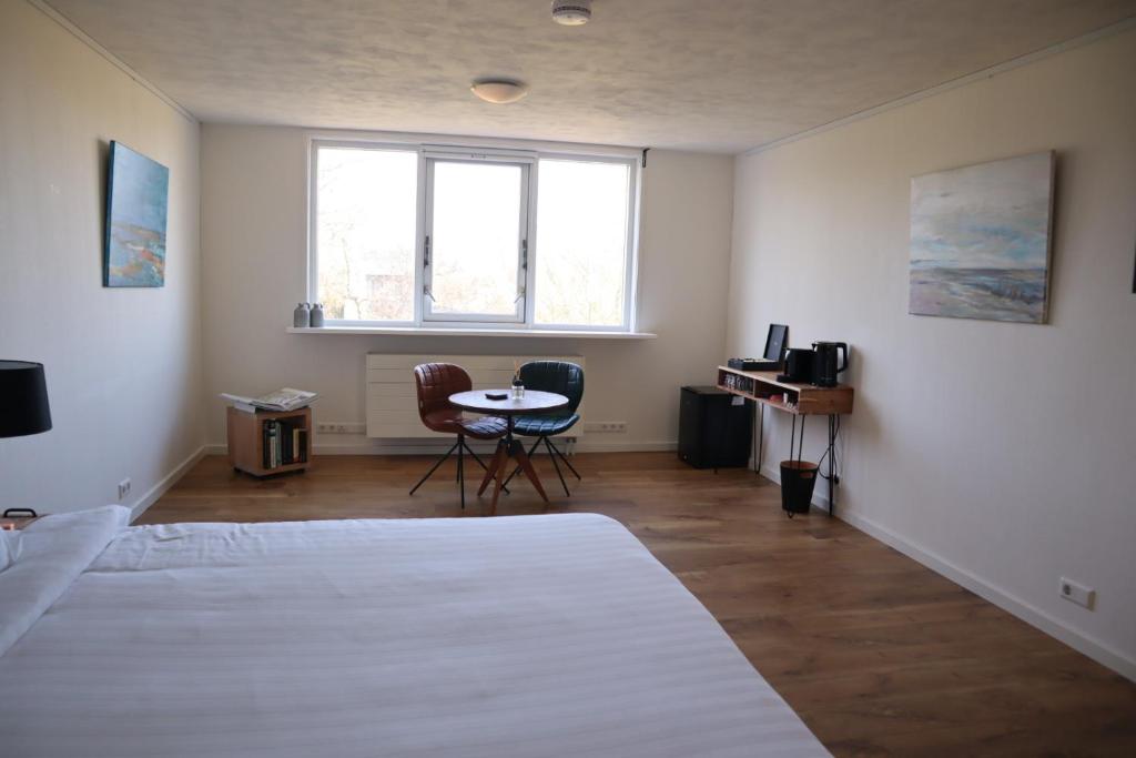 1 dormitorio con 1 cama, 1 mesa y 2 sillas en Bed & Coffee Maricoweg, en Den Burg