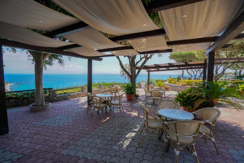 eine Terrasse mit Tischen und Stühlen und Meerblick in der Unterkunft Hotel Residence Sciaron in Capo Vaticano