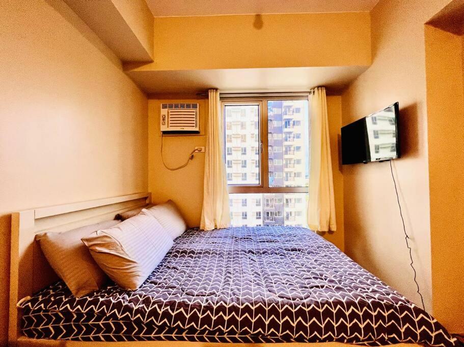 um pequeno quarto com uma cama e uma janela em I Best Value Studio em Iloilo