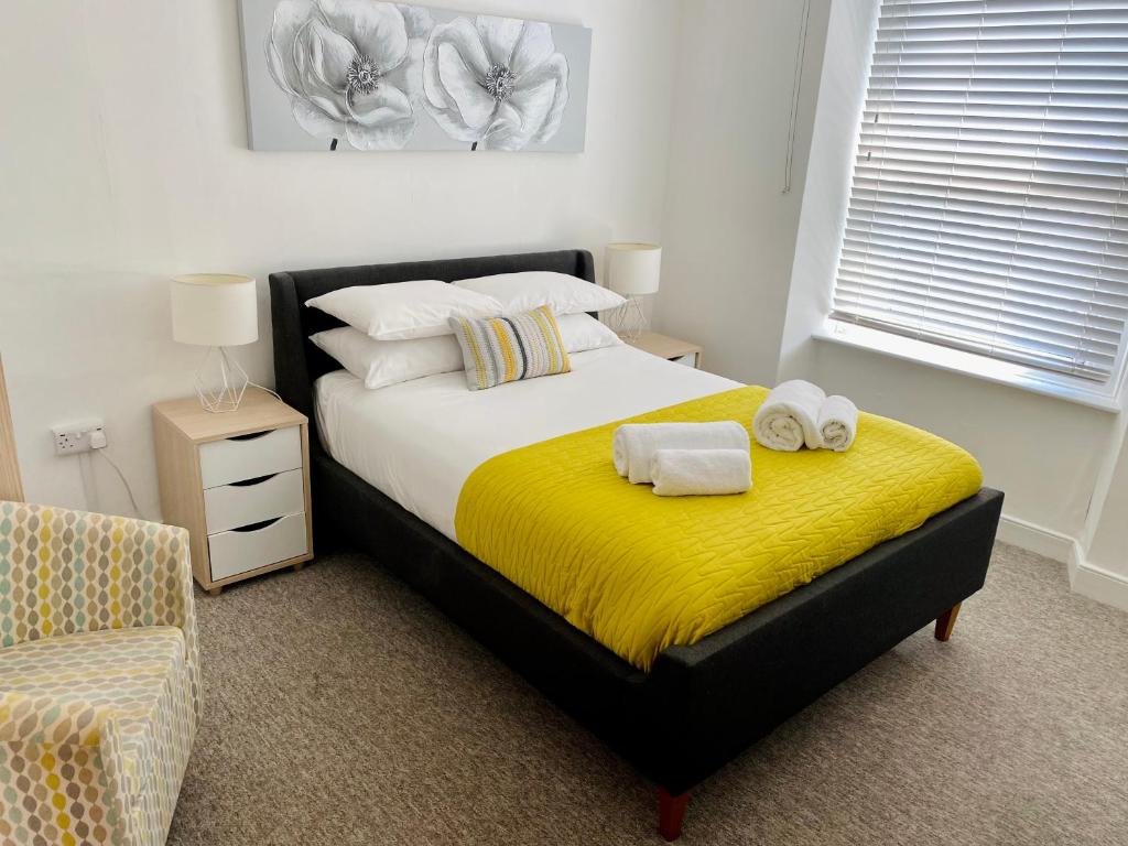 um quarto com uma cama com cobertor amarelo e uma cadeira em Liberty House em Weston-super-Mare