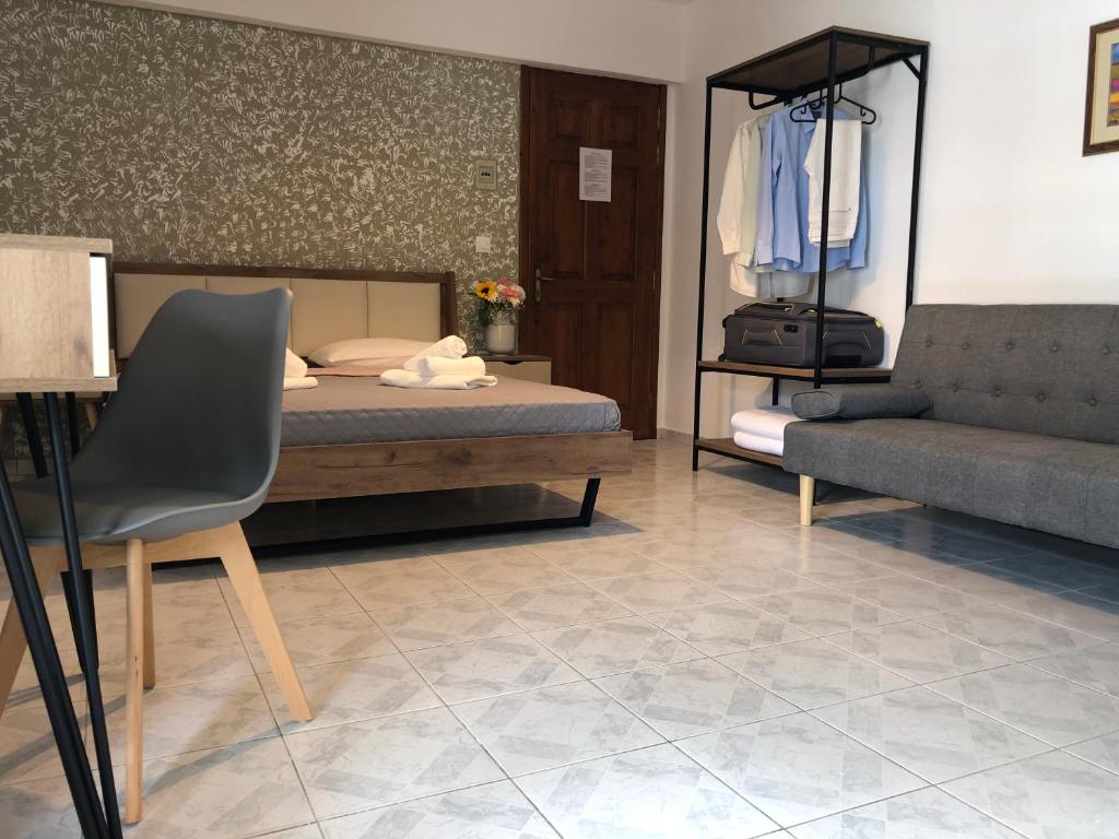 a bedroom with a bed and a couch and a chair at Armonia Guest House Skiathos in Skiathos Town