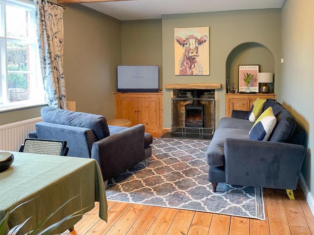 a living room with two couches and a fireplace at Corner Cottage in Alburgh
