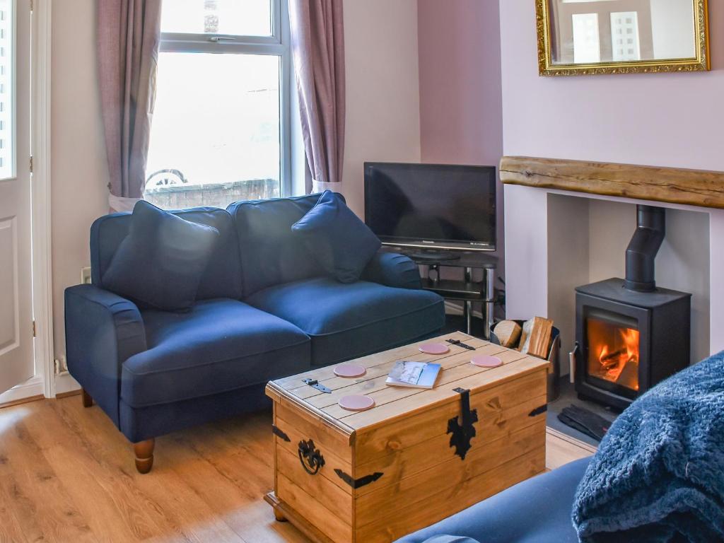 a living room with a blue couch and a fireplace at Sandy Paws in Gorleston-on-Sea