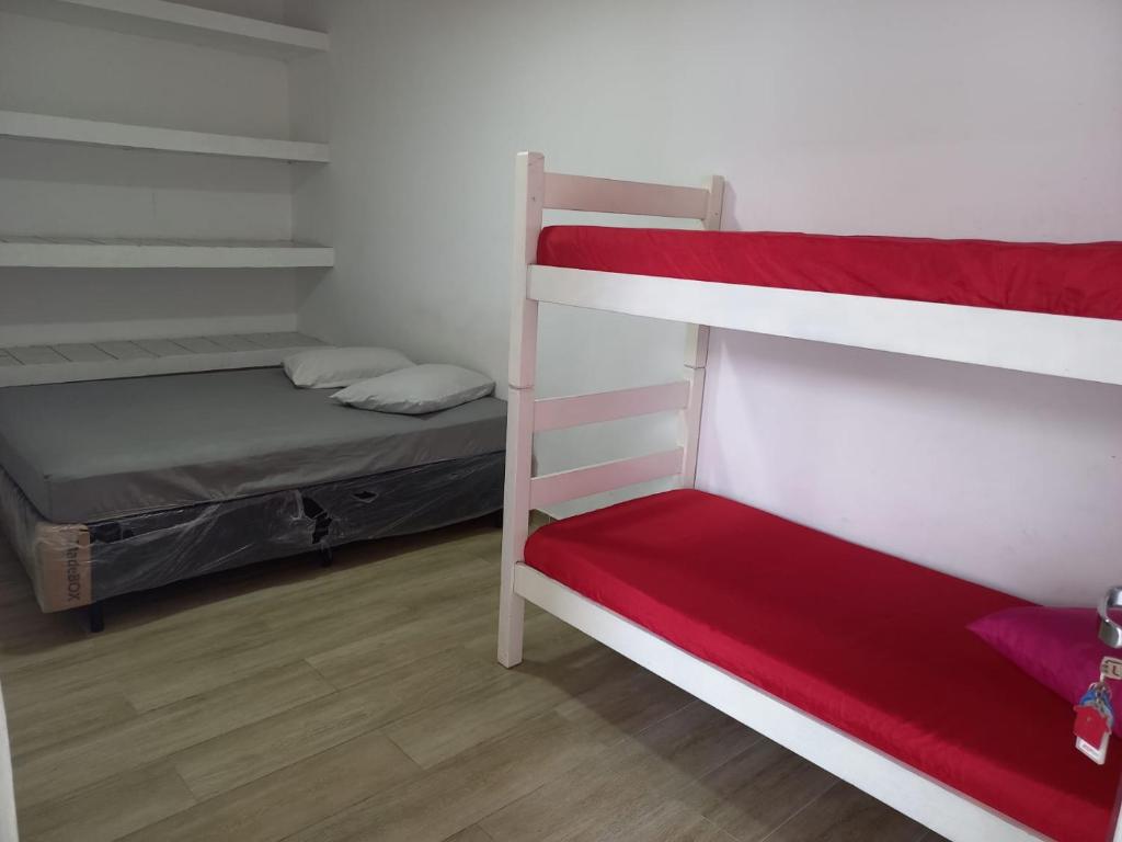a bedroom with two bunk beds and a red mattress at Hostel Mar da Vila in Praia Grande
