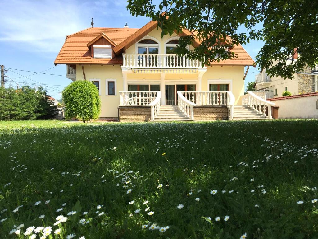 a house with a large yard with flowers at Csók Apartmanház in Balatonfüred