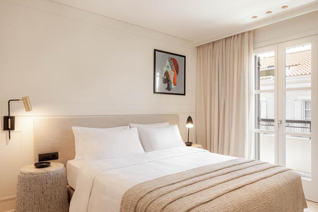 a bedroom with a large white bed and a window at Doryssa Theorem Hotel in Pythagoreio
