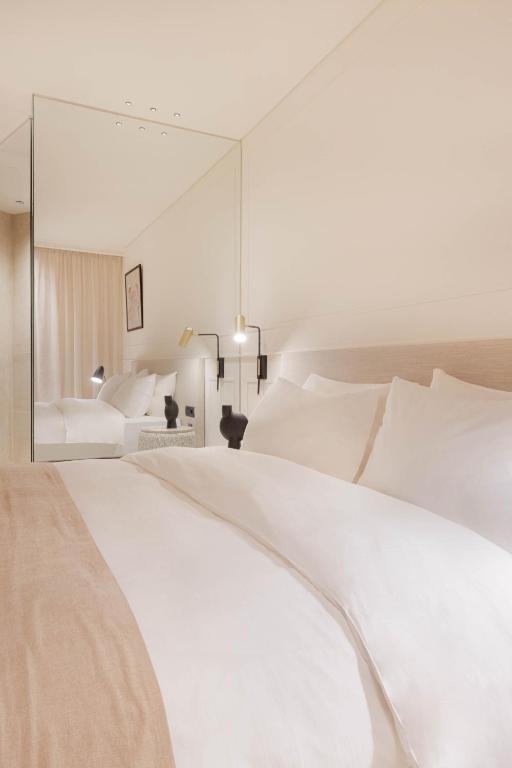 a bedroom with a large white bed and a mirror at Doryssa Theorem Hotel in Pythagoreio