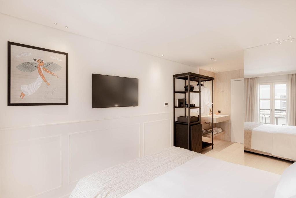 a white bedroom with a bed and a tv on the wall at Doryssa Theorem Hotel in Pythagoreio
