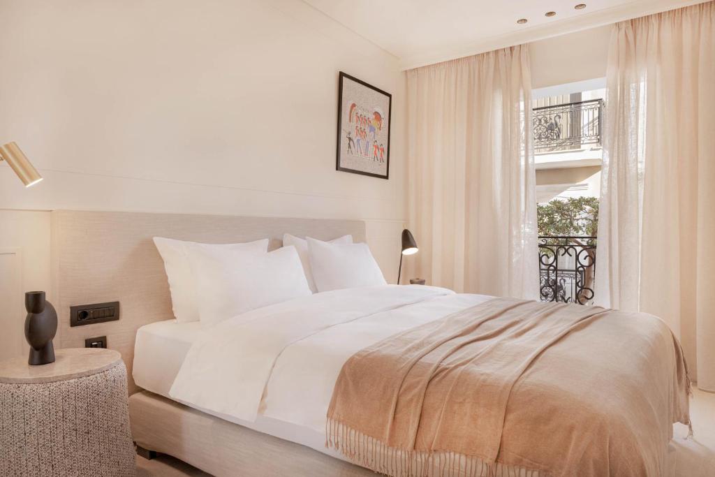 a white bedroom with a bed and a window at Doryssa Theorem Hotel in Pythagoreio