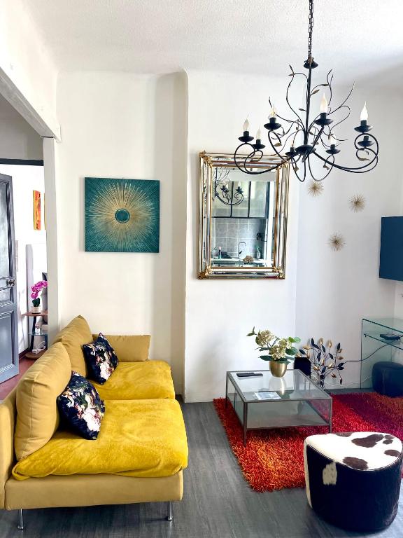 un salon avec un canapé jaune et un lustre dans l'établissement CÔTE D’AZUR Appart spacieux / lumineux, à Toulon