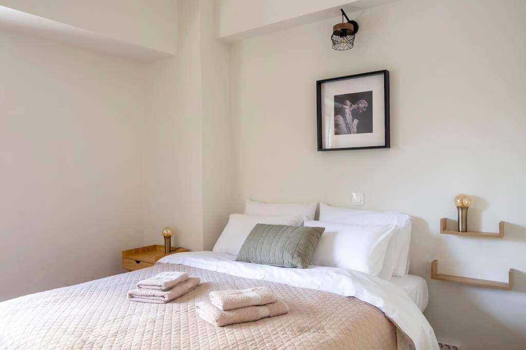a white bedroom with two towels on a bed at Cozy apartment in the best part of Pagkrati in Athens