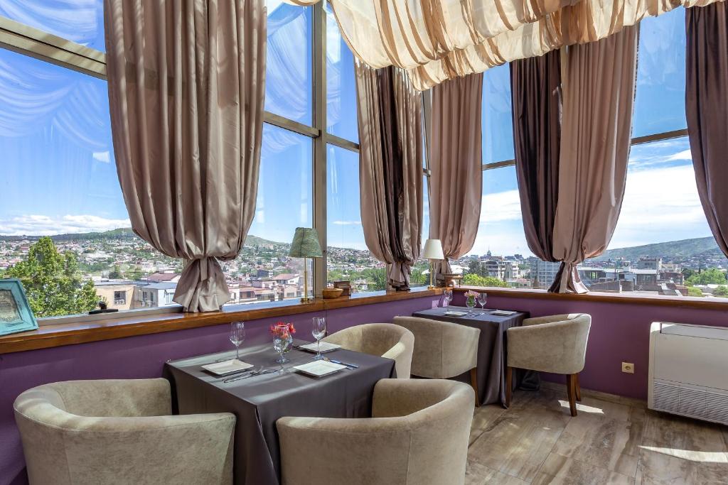 un restaurante con 2 mesas y sillas y ventanas grandes en A5 Hotel, en Tiflis