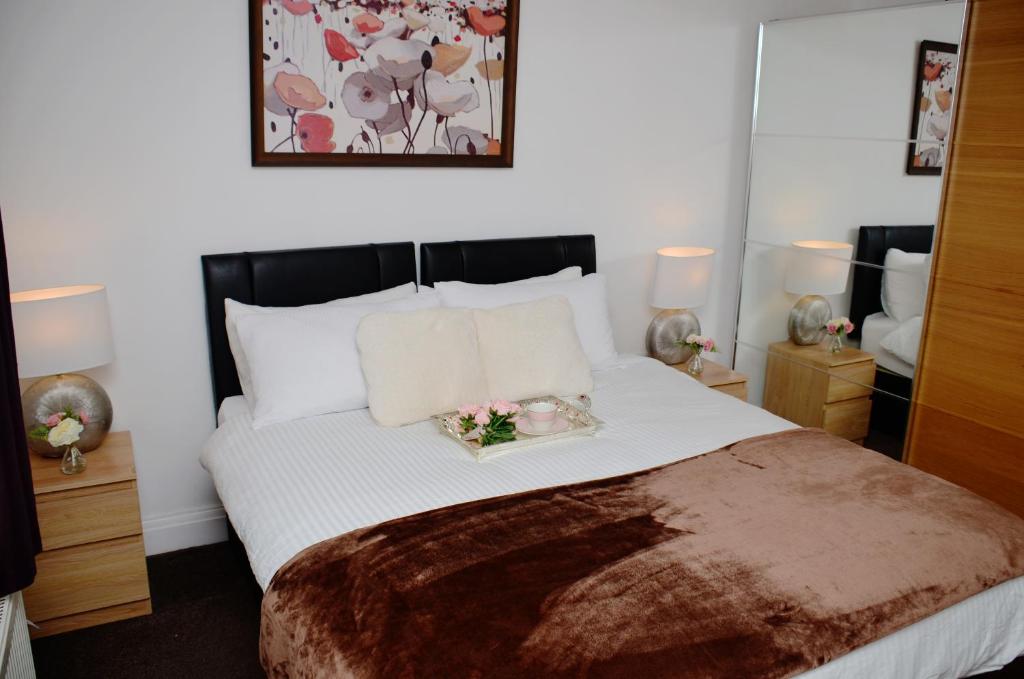 ein Schlafzimmer mit einem großen weißen Bett mit Blumen darauf in der Unterkunft 29EW Dreams Unlimited Serviced Accommodation- Staines - Heathrow in Stanwell