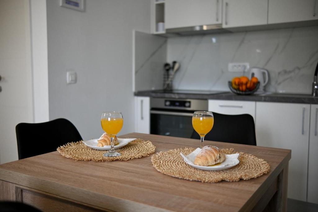 uma mesa de cozinha com 2 copos de sumo de laranja e croissants em Golden Neretva apartments em Metković