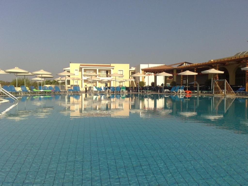 a large swimming pool with chairs and umbrellas at Aktea Beach Village in Ayia Napa