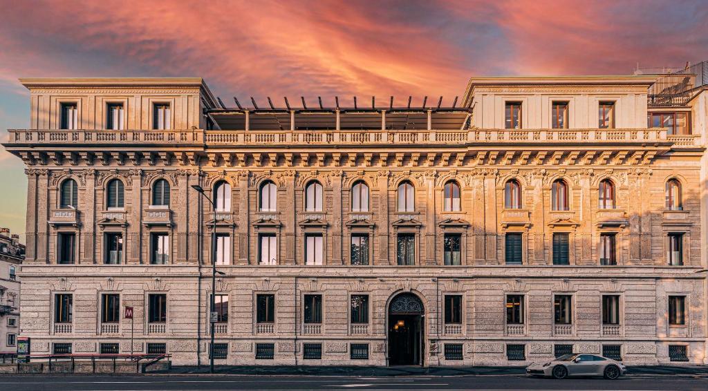 duży budynek z samochodem zaparkowanym przed nim w obiekcie Casa Cipriani Milano w Mediolanie