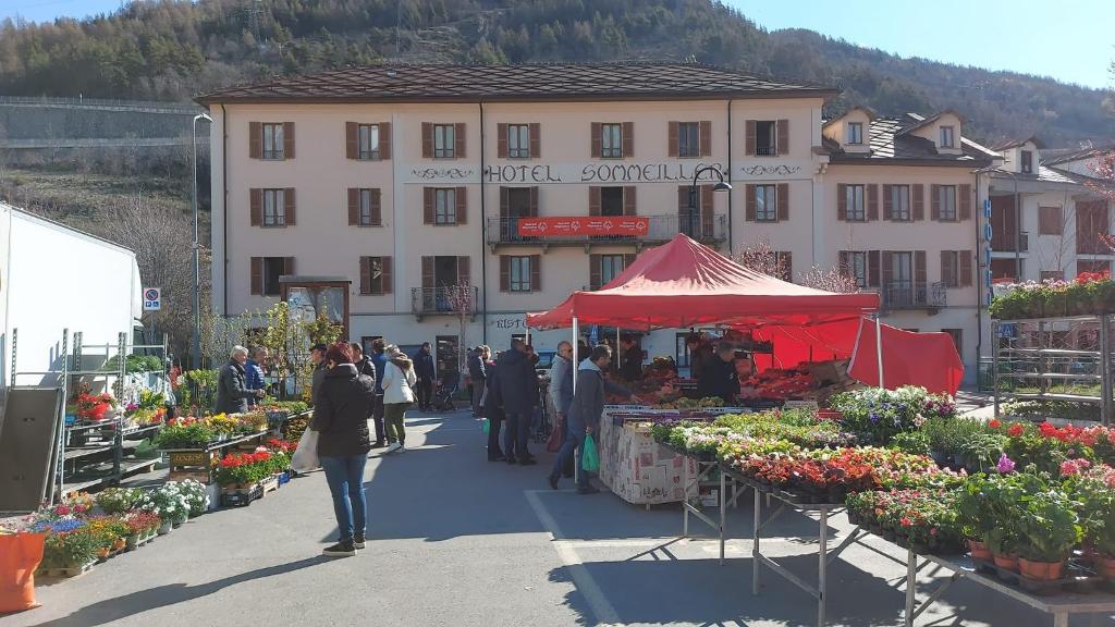 a group of people walking around an outdoor market with flowers at Hotel Sommeiller in Bardonecchia