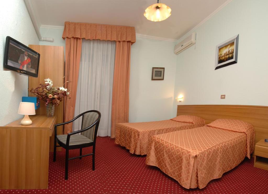 une chambre d'hôtel avec deux lits et une chaise dans l'établissement Hotel Sorriso, à Sanremo