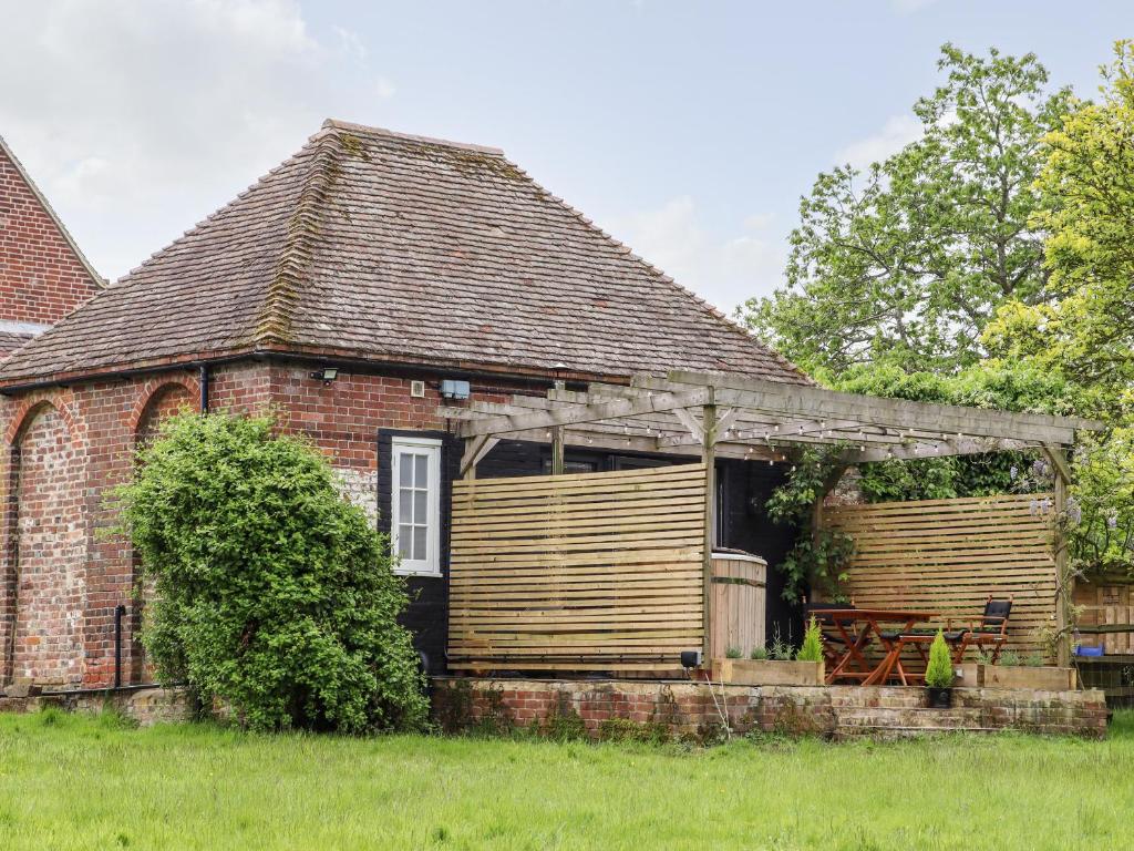 una antigua casa de ladrillo con pérgola de madera en The Snug at Pickelden Farmhouse en Canterbury