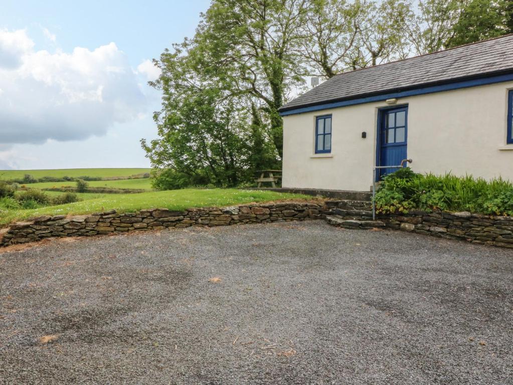 a white house with a blue door and a stone wall at Ballyvoreen in Glandore