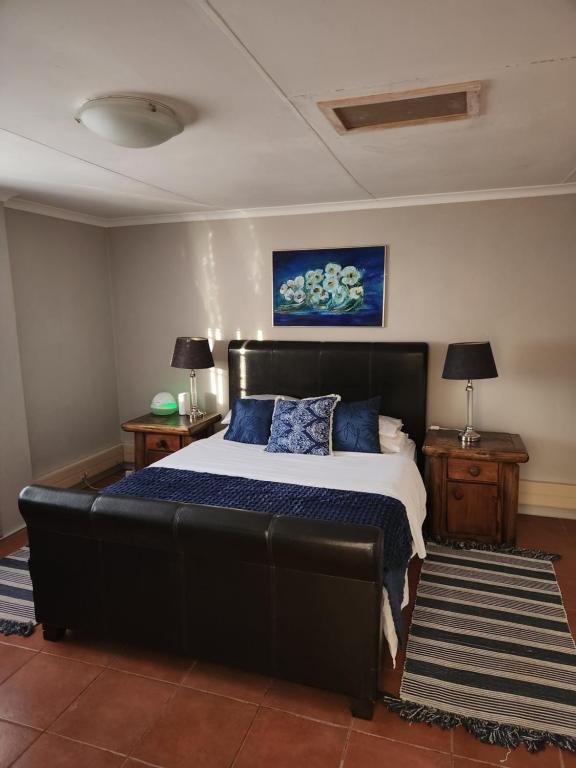a bedroom with a large black bed with blue pillows at One bedroom house in Boksburg