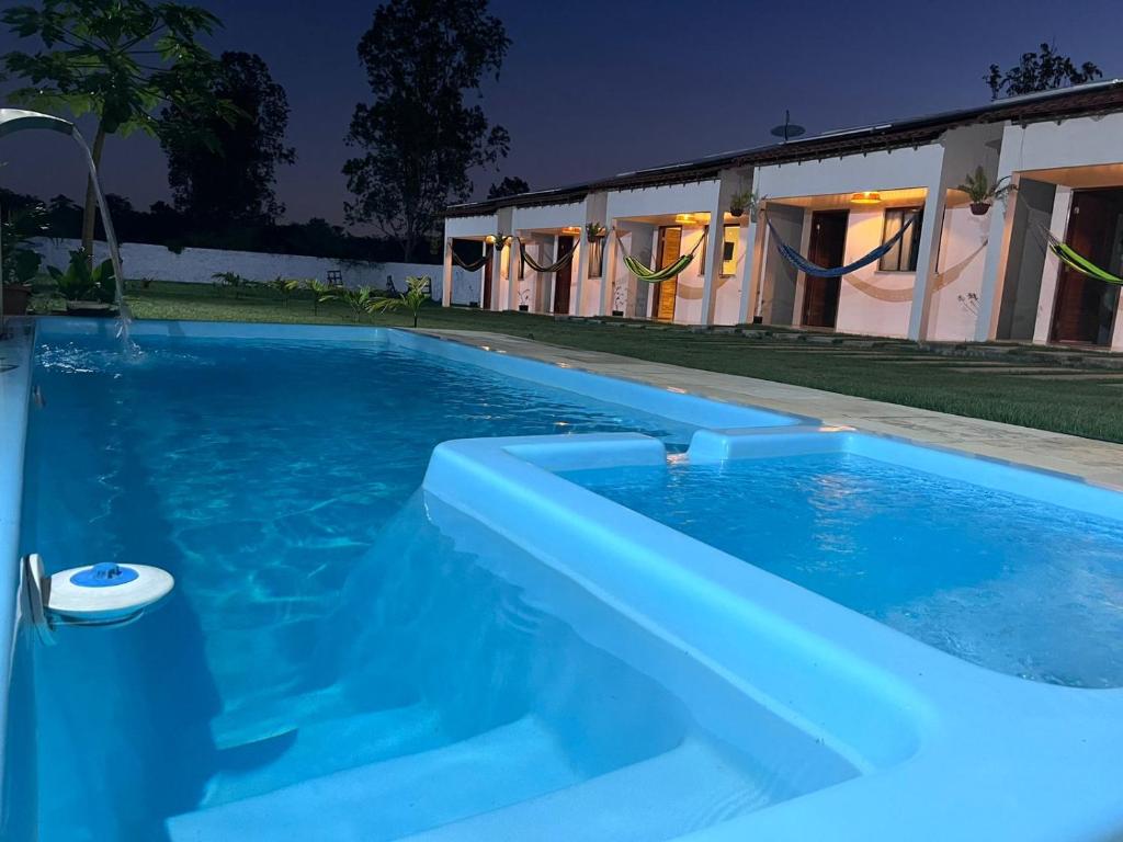 a blue swimming pool in front of a house at Pousada Mangaba in Barreirinhas