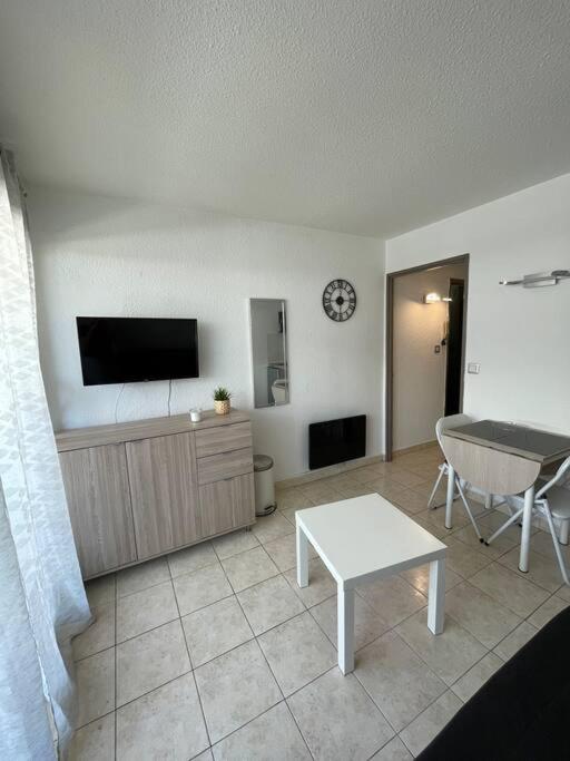 un salon avec une télévision à écran plat et une table dans l'établissement Superbe studio au bord de la mer à Sete, à Sète