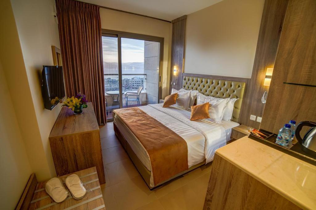 De-Lara hotel في العقبة: غرفه فندقيه بسرير وشرفه