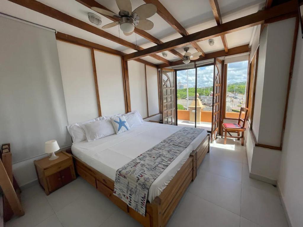 um quarto com uma cama, uma ventoinha de tecto e uma janela em 7CN-3 CASA DE 7 HABITACIONES EN EL CENTRO HISTORICO em Cartagena das Índias