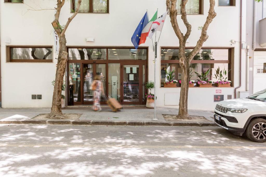 アルゲーロにあるホテル ドモメアのスケートボードを持つ建物の前を歩く者