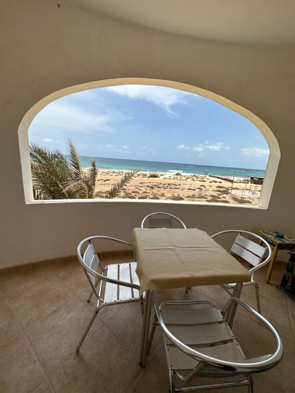 een tafel en stoelen in een kamer met uitzicht op het strand bij sea View Nautilus free wi-fi Sal Rei in Sal Rei