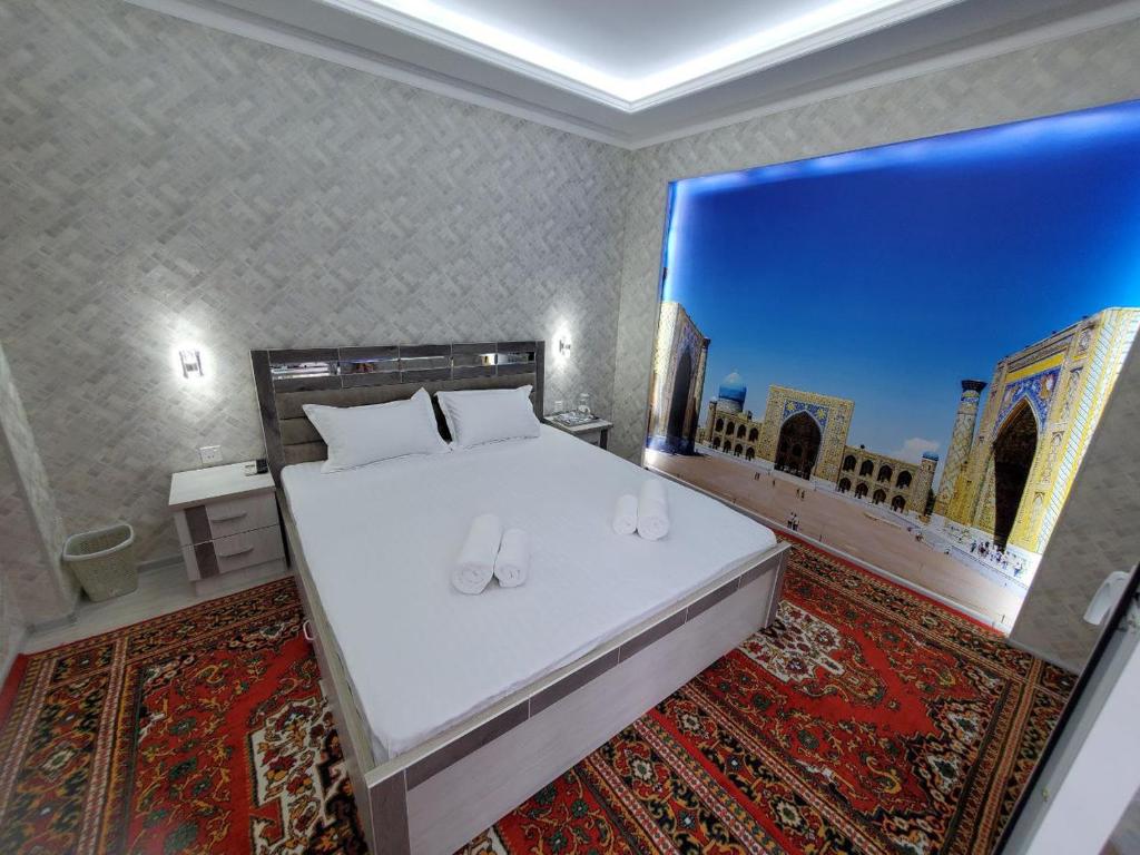 1 dormitorio con 1 cama con una pintura en la pared en Nursultan Grand Guest House, en Samarkand