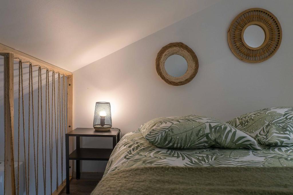 een slaapkamer met een bed en twee spiegels aan de muur bij Résidence Le Celest - Appartements climatisés - Centre ville in Vichy