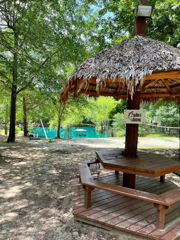 a wooden gazebo with a bench and a straw hut at Casita with Swimming Pond & Sand Volleyball Access in Montgomery
