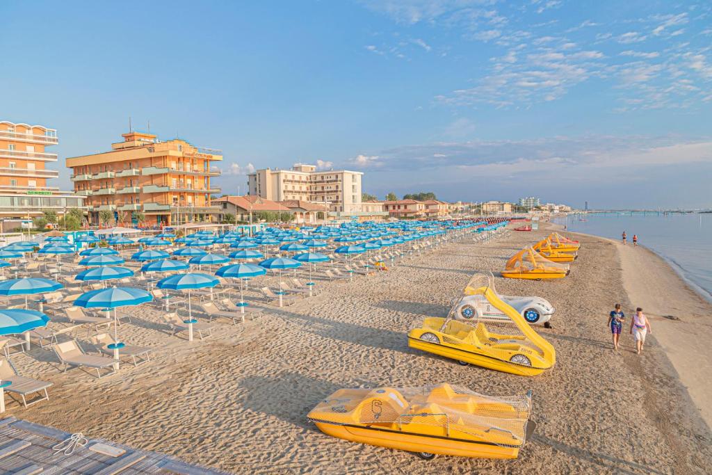 una playa con un montón de barcos amarillos y sombrillas en Hotel Cola Frontemare, en Bellaria-Igea Marina