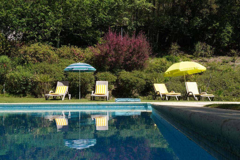 un gruppo di sedie e ombrelloni accanto alla piscina di Casa das Camélias a Guimarães