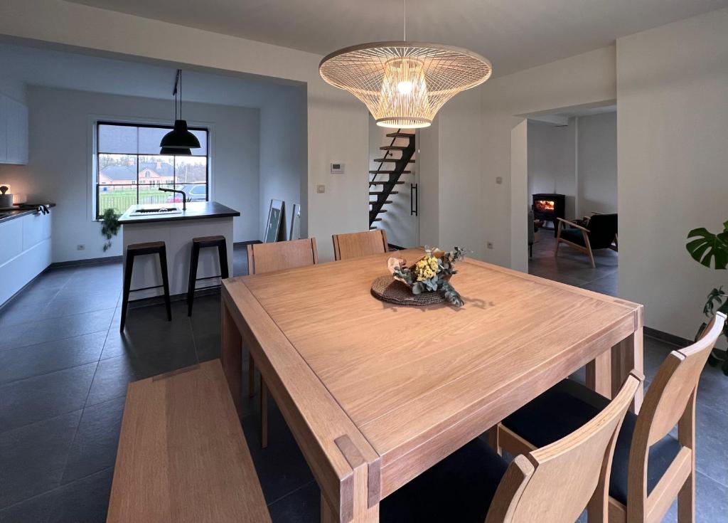 a dining room and kitchen with a wooden table and chairs at De Bovenbuur in Lummen