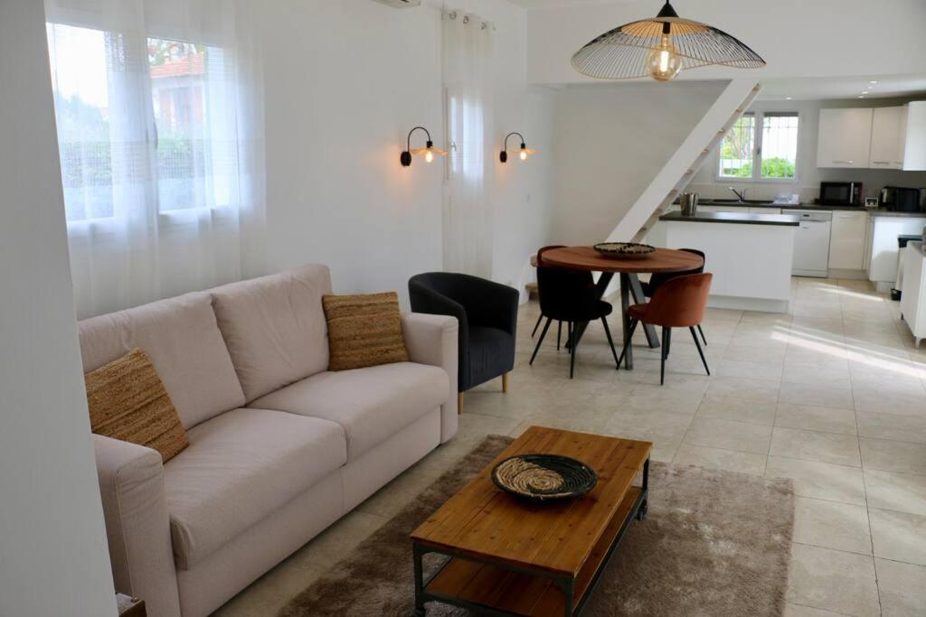 een woonkamer met een witte bank en een tafel bij Maison idéale à 3min de la plage in Mandelieu-la-Napoule
