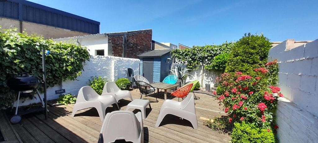 d'un patio avec des chaises blanches, des tables et des fleurs. dans l'établissement Home Sweet Home, au Mans