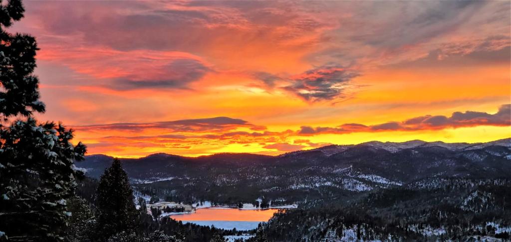 una puesta de sol en las montañas con un lago en High Sierra Condominiums en Ruidoso