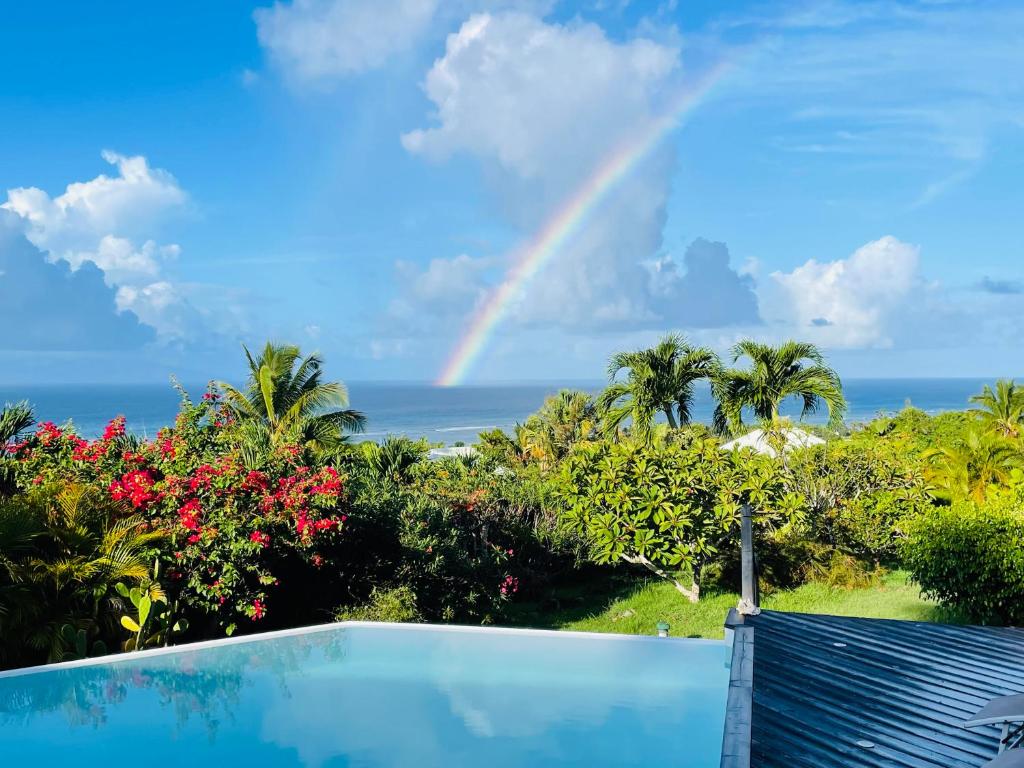 a rainbow over the ocean with a swimming pool at Villa Libellule in Grand-Bourg