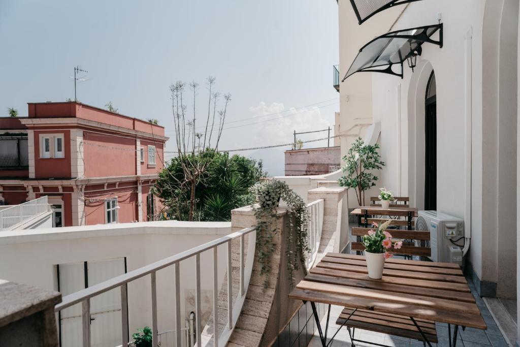 een balkon met een houten tafel en een parasol bij Il Cortile by Vista Napoli in Napels