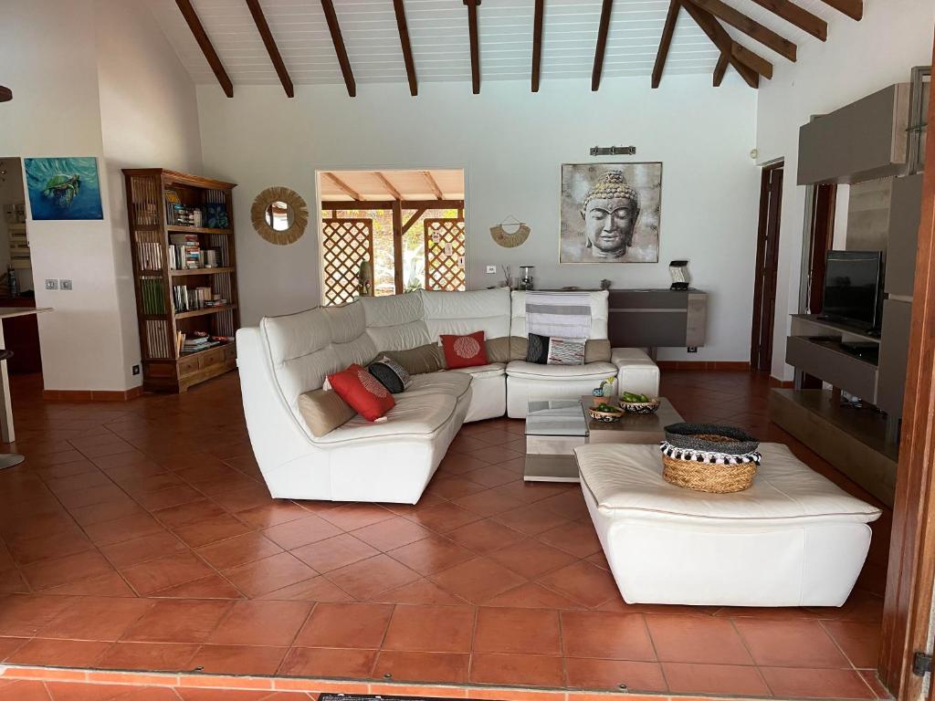 a living room with white couches and a tile floor at Villa Libellule in Grand-Bourg
