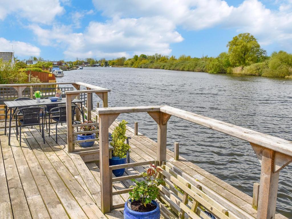 a wooden dock with a table and chairs on a river at Evening Glory in Brundall