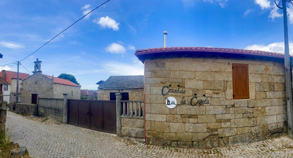 a brick building with a gate on a street at Casinhas da Capela in Tourém
